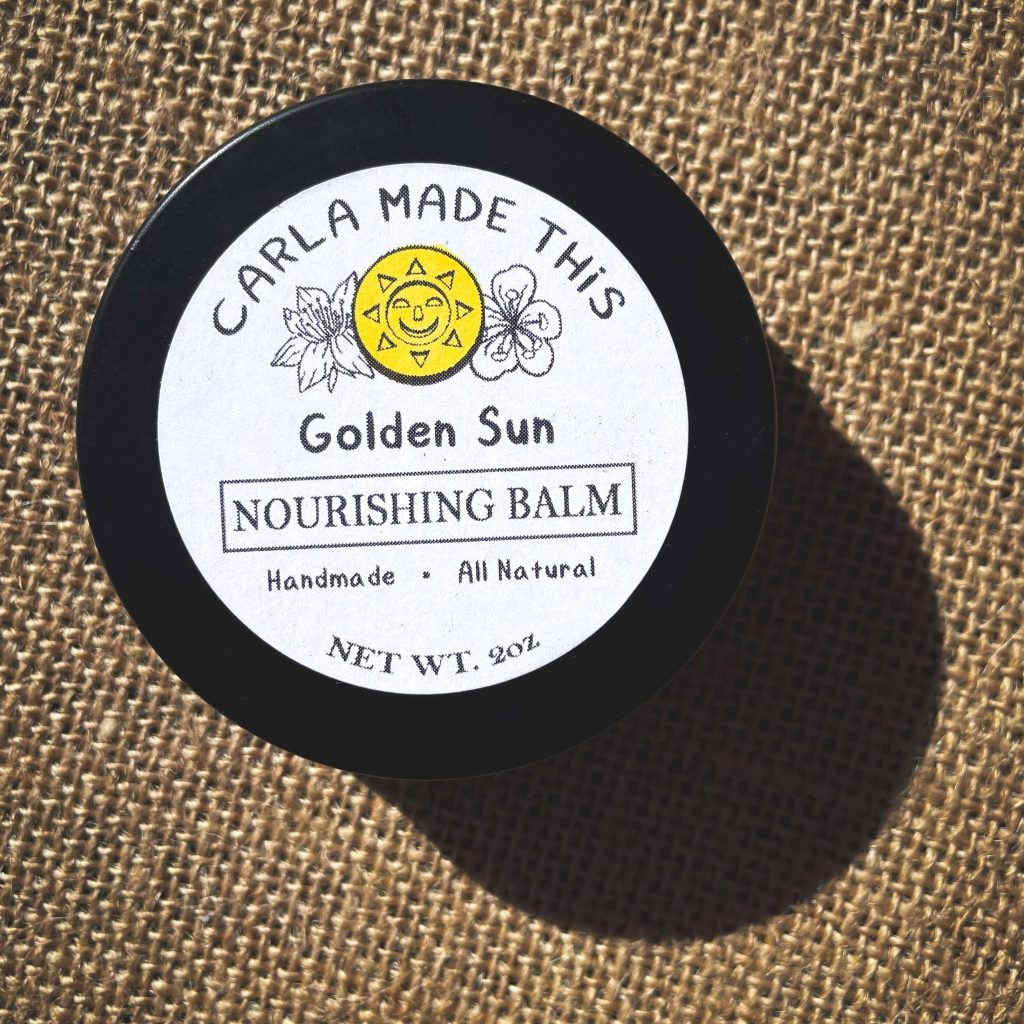 A black tin labelled golden sun nourishing balm on a textured background.